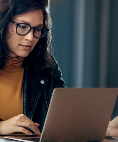 Image of women wearing a leather jacket and yellow top looking at a computer screen