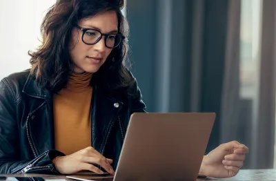 Image of women wearing a leather jacket and yellow top looking at a computer screen