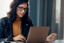 Image of women wearing a leather jacket and yellow top looking at a computer screen