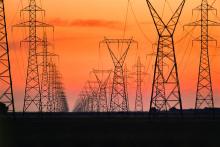 Series of high-voltage power transmission towers carrying electricity across a wide service corridor.