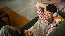 Streaming study 2024: A woman lying on the couch watching a tablet with headphones on